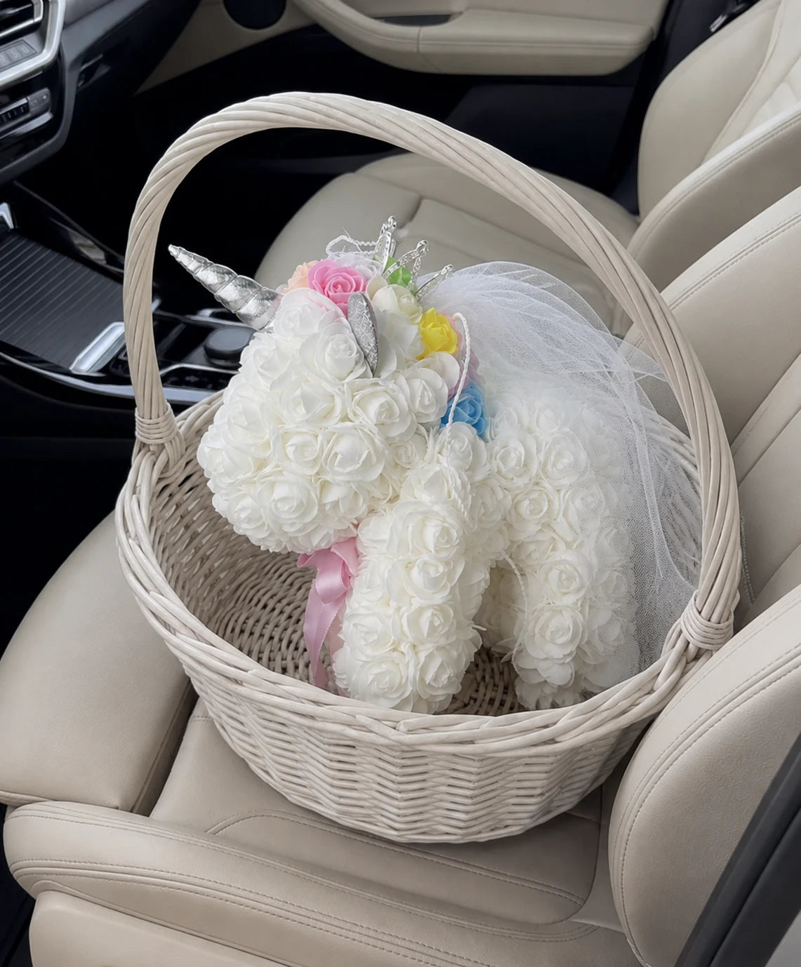 White rose unicorn styled in a woven gift basket on a car seat