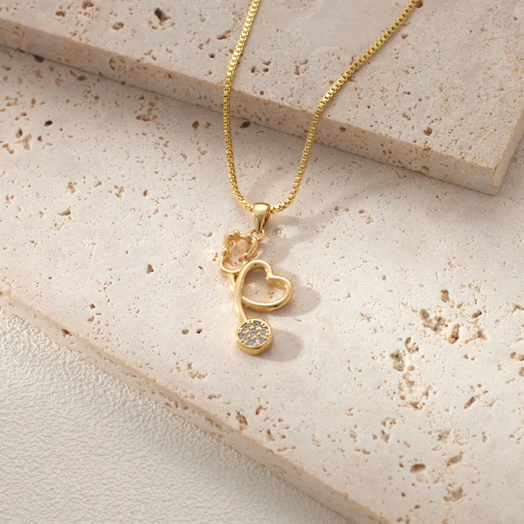 Nahaufnahme des herzförmigen Designs der goldenen Stethoskop-Halskette mit glänzendem Zirkonia