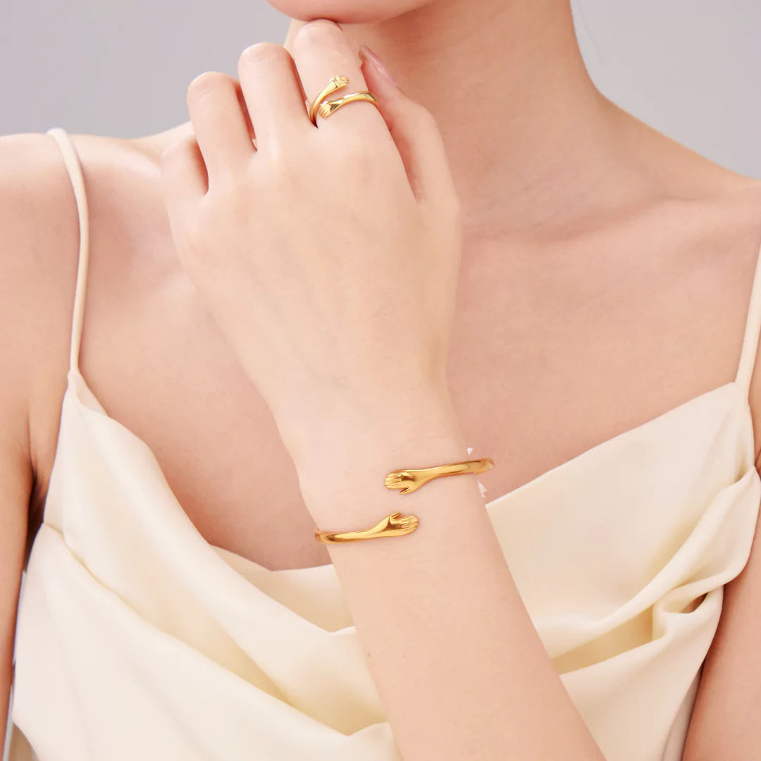 Das goldene Umarmungsarmband am Handgelenk einer Frau – zartes Symbol tiefer Verbundenheit