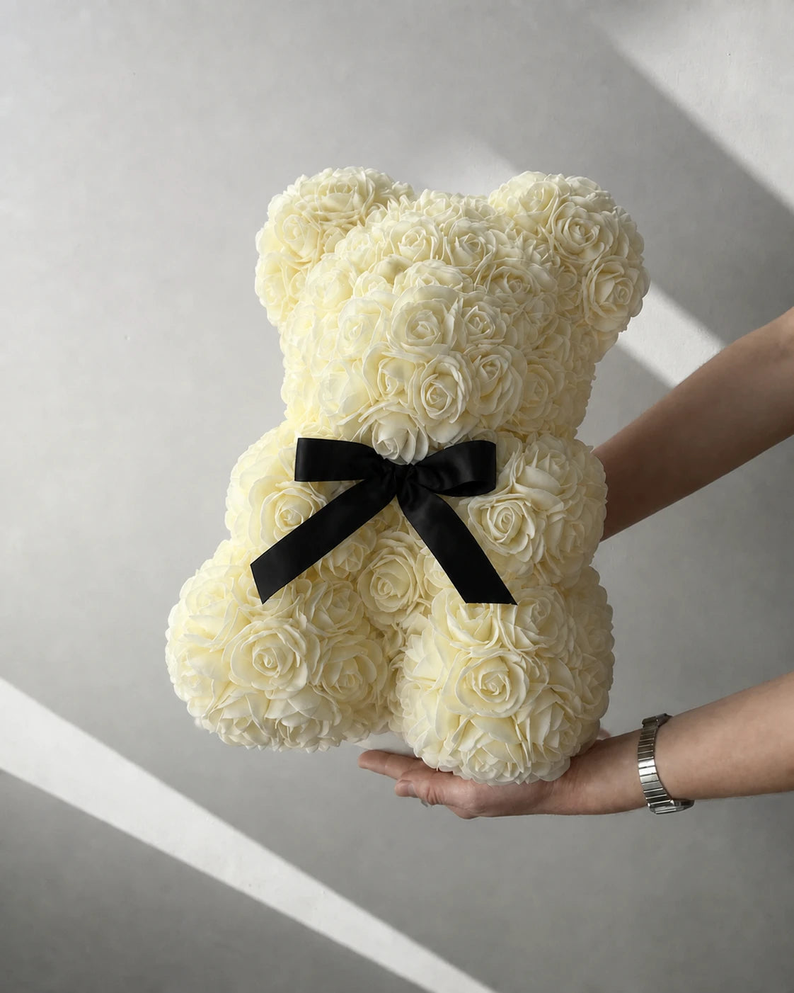 Ivory rose teddy bear presented beside a softly lit window
