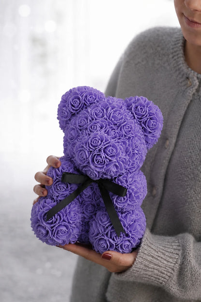 Lavender rose teddy bear cradled low against a soft grey knit