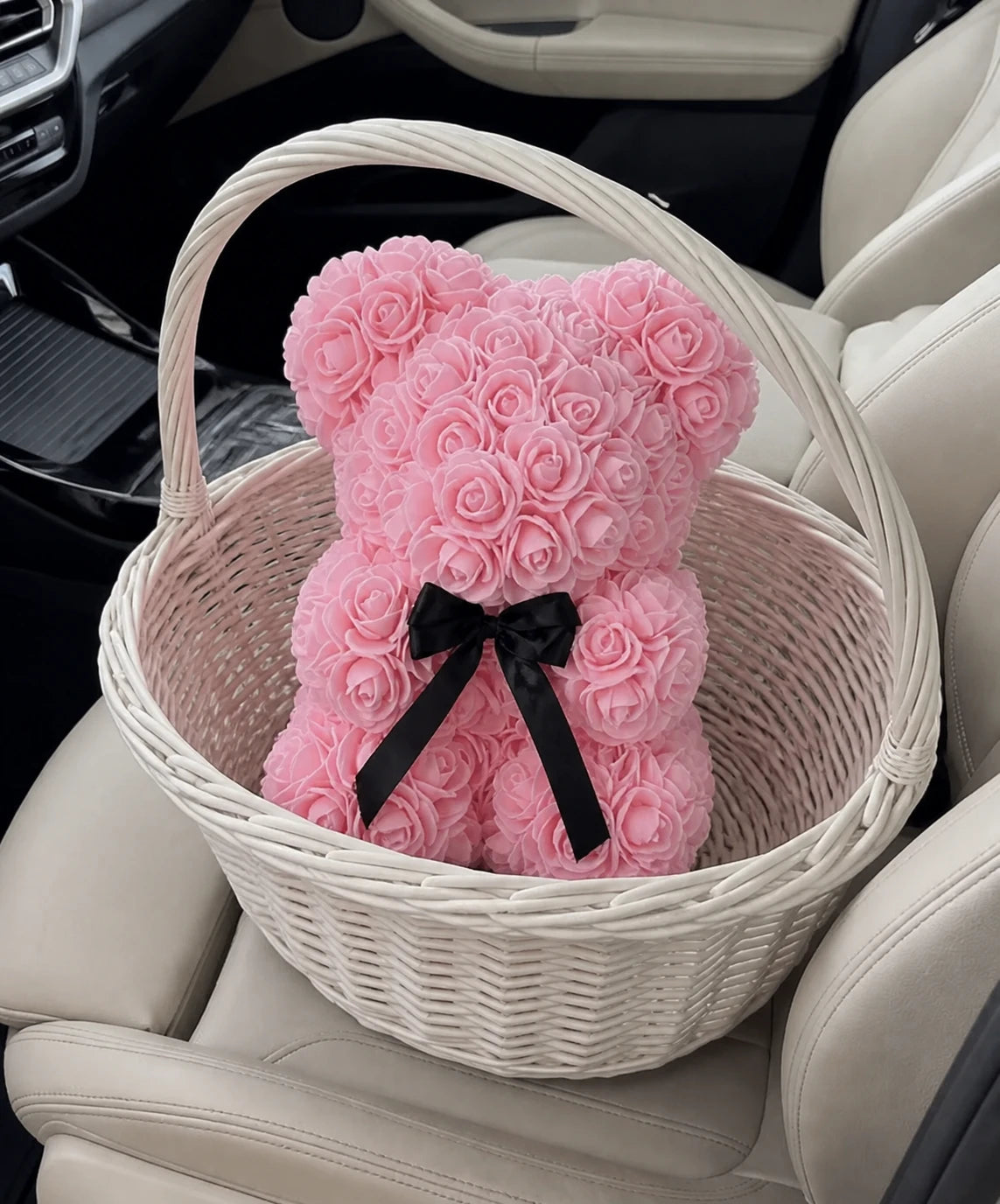 Light pink rose teddy bear styled in a woven gift basket on a car seat