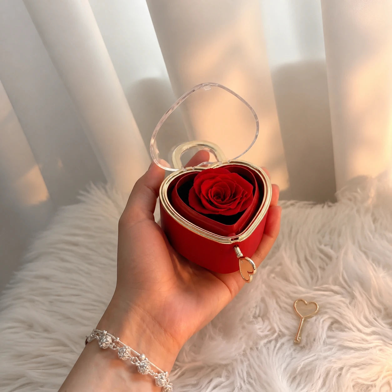Hand hält eine rote Herzschmuckbox mit Seifenrose und Schlüssel