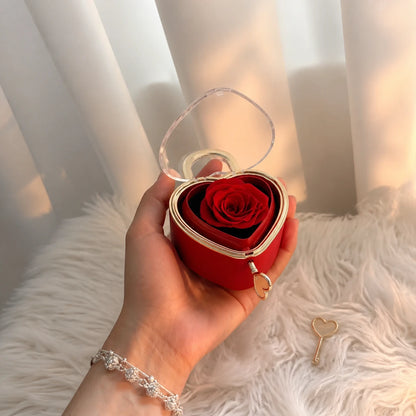 Hand hält eine rote Herzschmuckbox mit Seifenrose und Schlüssel