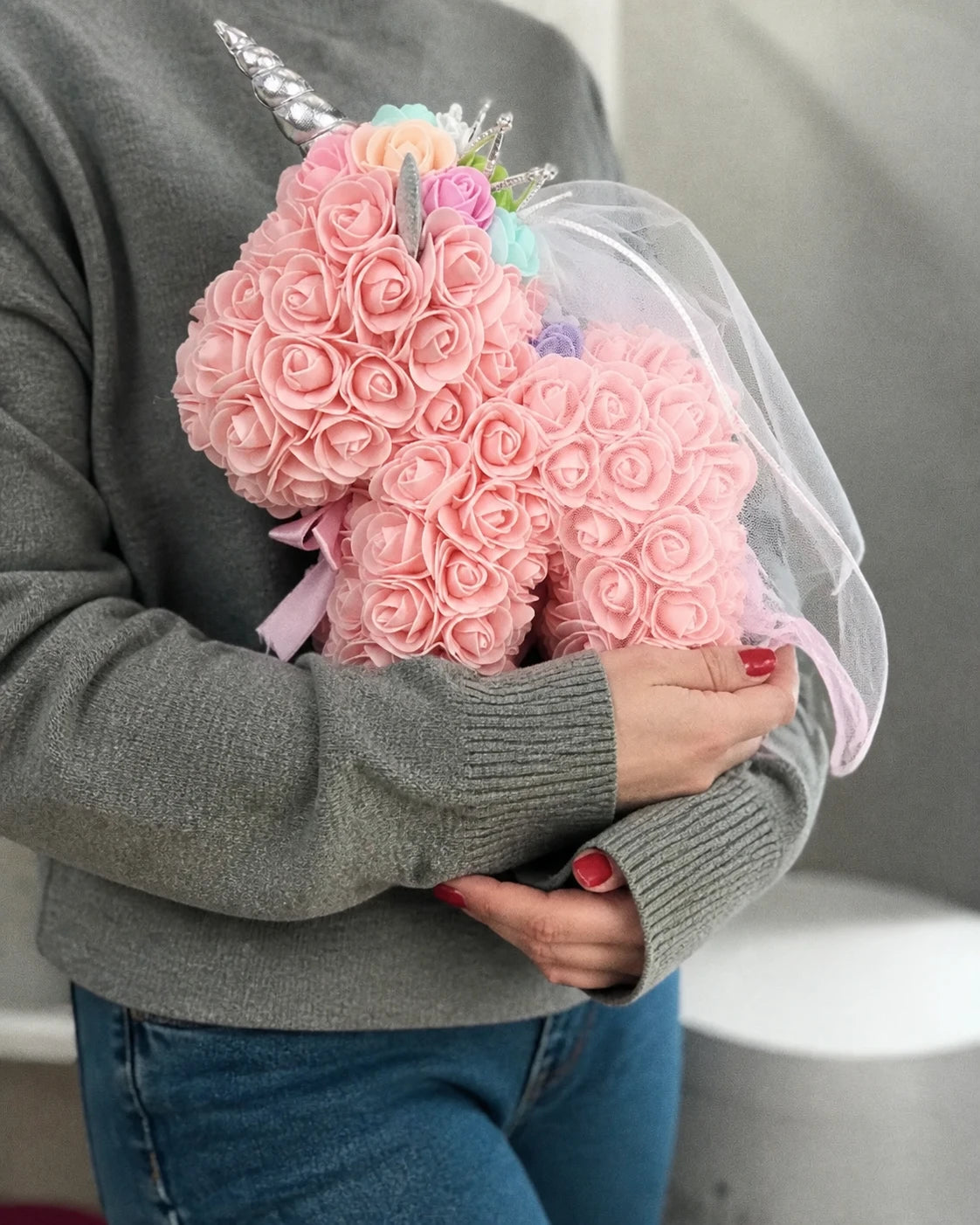 Peach rose unicorn gift cradled with a soft grey sweater