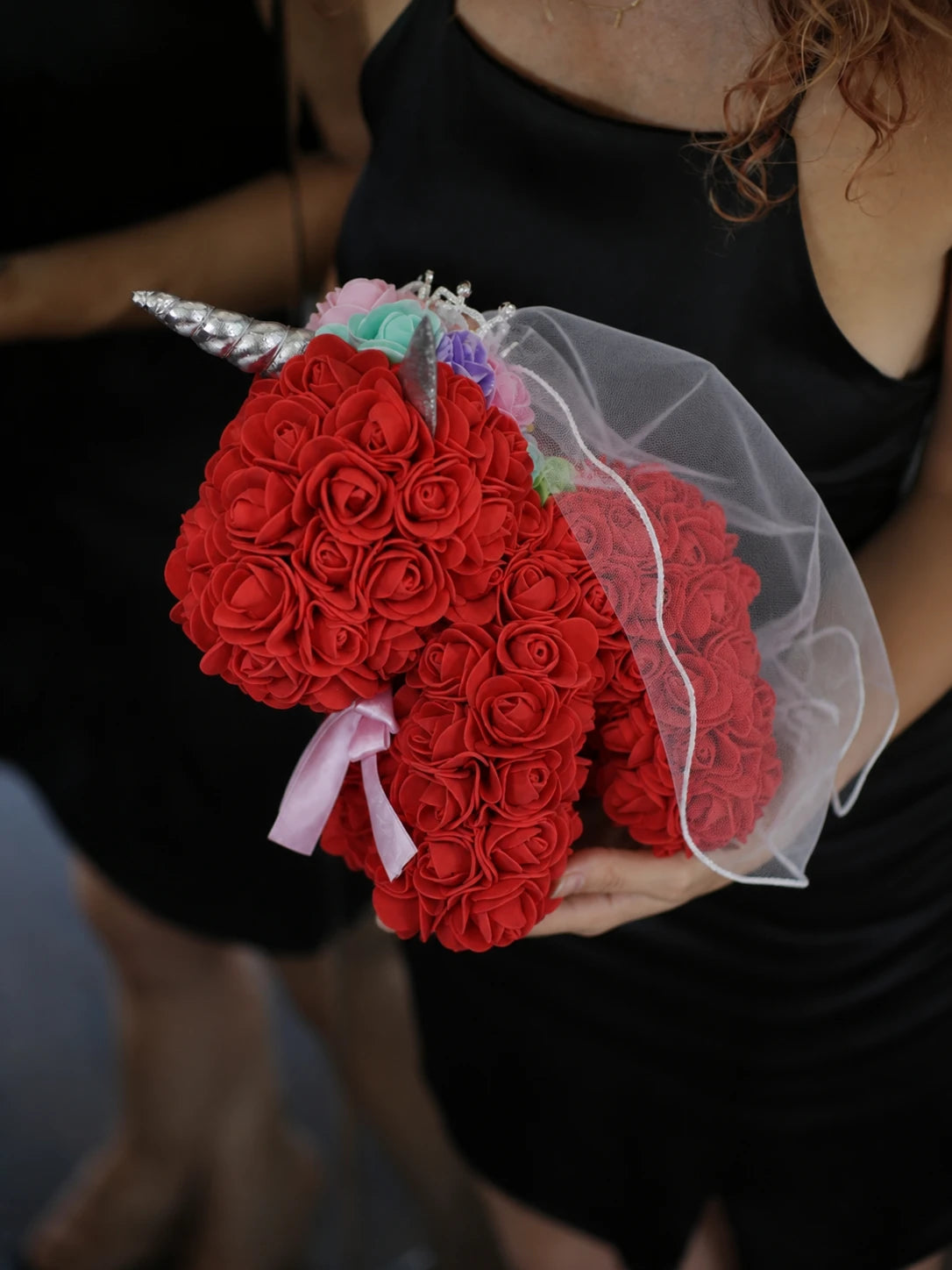 Red rose unicorn keepsake held against a black dress