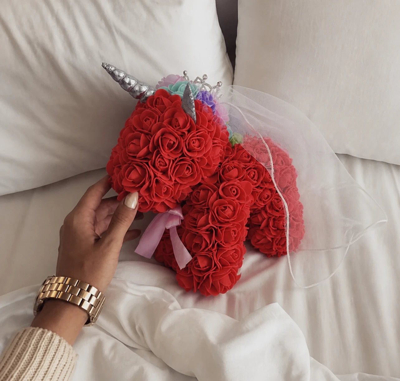 Red rose unicorn keepsake beside a bed with a natural hand interaction