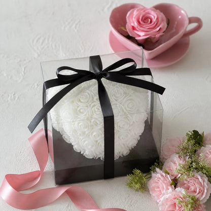 Weißes Rosenherz in transparenter Geschenkbox mit rosafarbenen Blumen