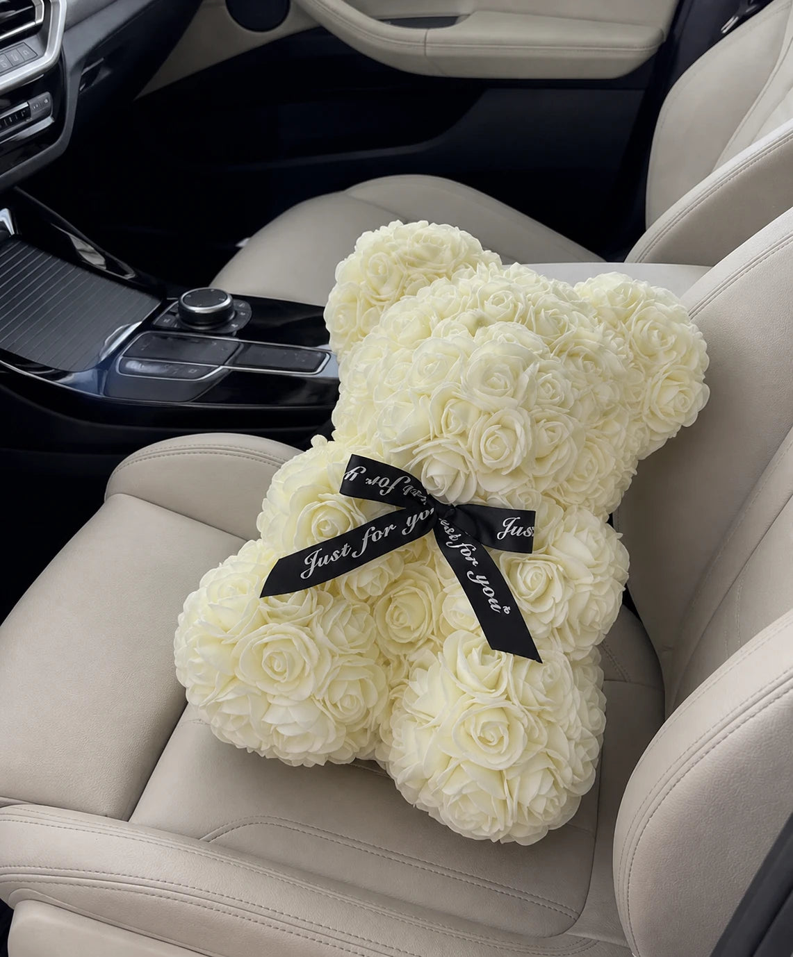 Ivory rose teddy bear displayed on a neutral car seat