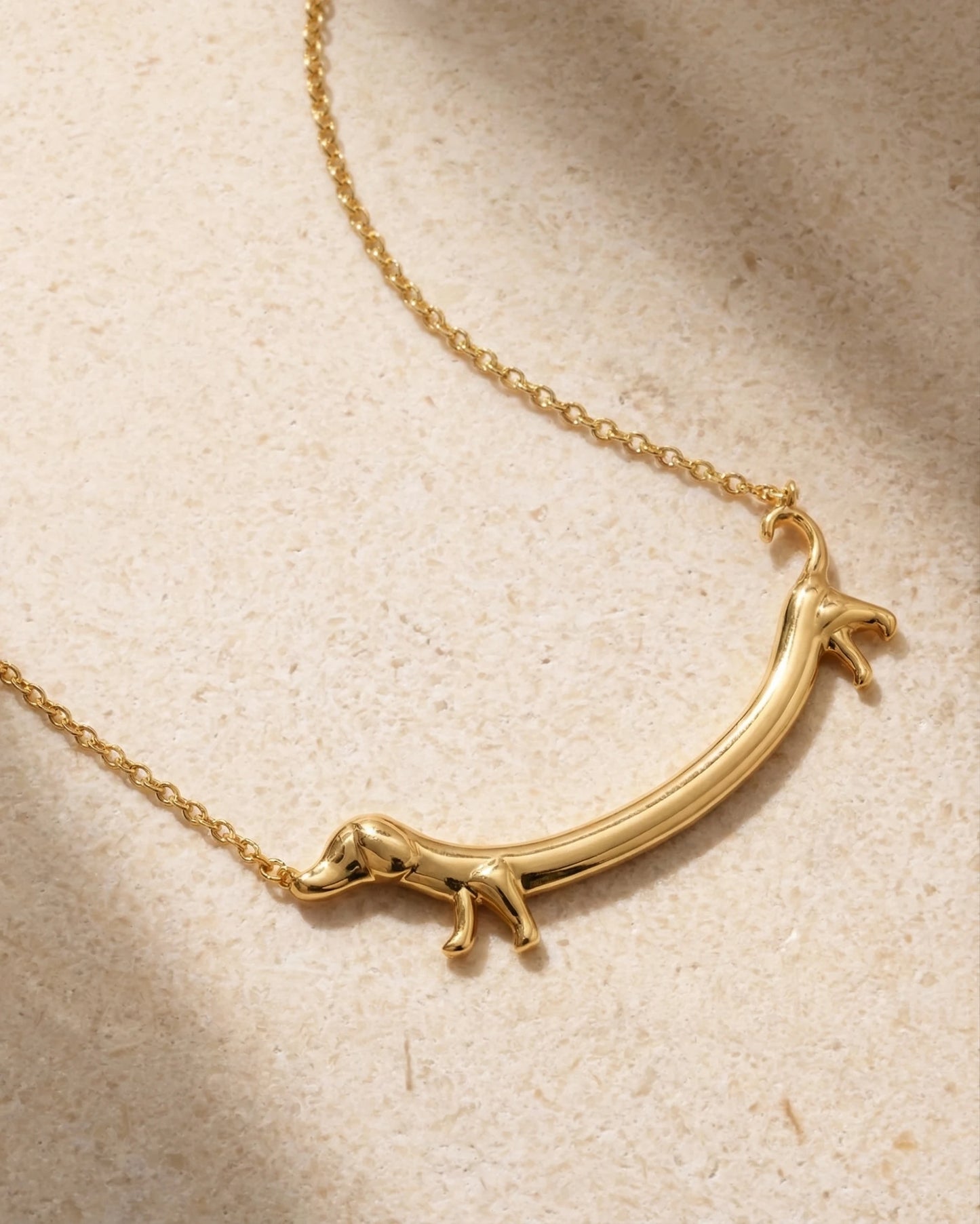 Goldene Dackel Halskette auf Marmor-Hintergrund