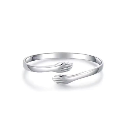 Nahaufnahme des Umarmungsarmbands aus Sterlingsilber mit zwei sich umarmenden Figuren